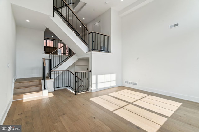 stairway featuring light wood-type flooring and a high ceiling