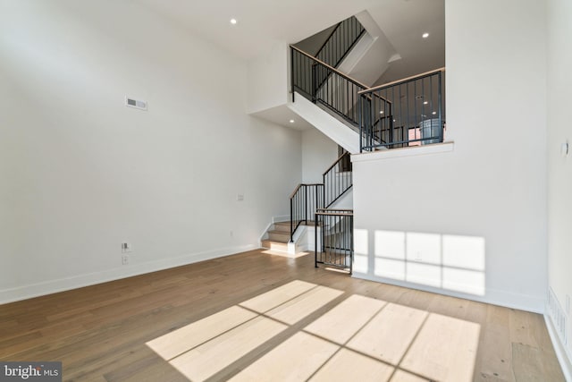 unfurnished living room featuring hardwood / wood-style floors and a towering ceiling