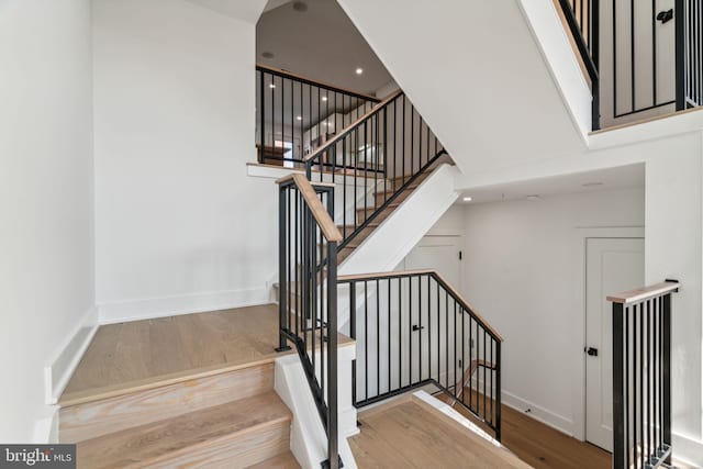 staircase with hardwood / wood-style floors and a high ceiling