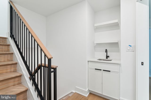 stairs with light hardwood / wood-style floors and sink