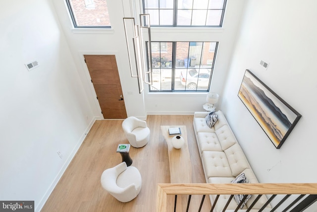 living room with light hardwood / wood-style floors and a high ceiling