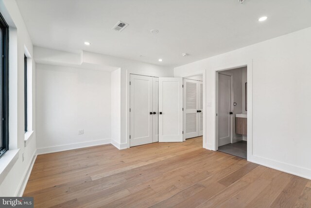 unfurnished bedroom featuring light hardwood / wood-style flooring and connected bathroom