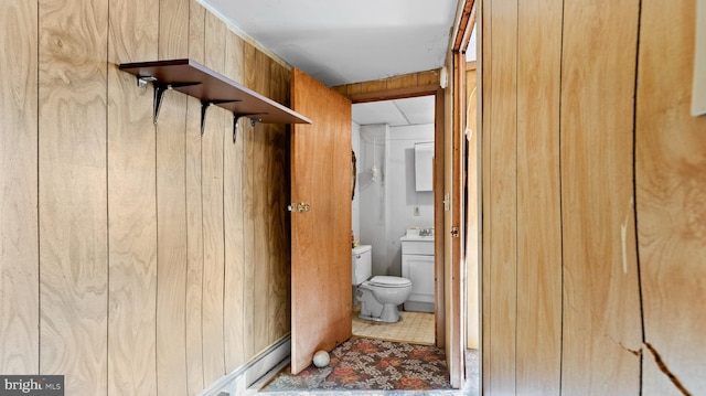 interior space featuring wooden walls, sink, and light tile floors