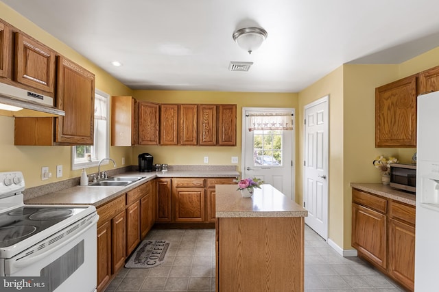 kitchen with white appliances, a center island, a healthy amount of sunlight, and sink