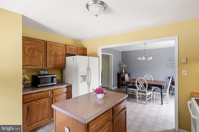 kitchen with pendant lighting, a center island, white appliances, and an inviting chandelier