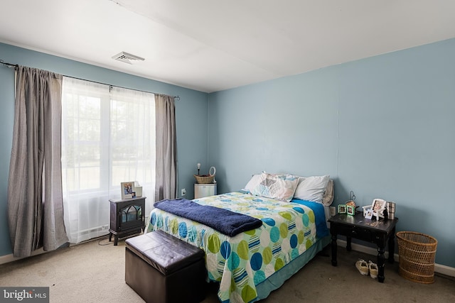 bedroom featuring carpet flooring and a wood stove