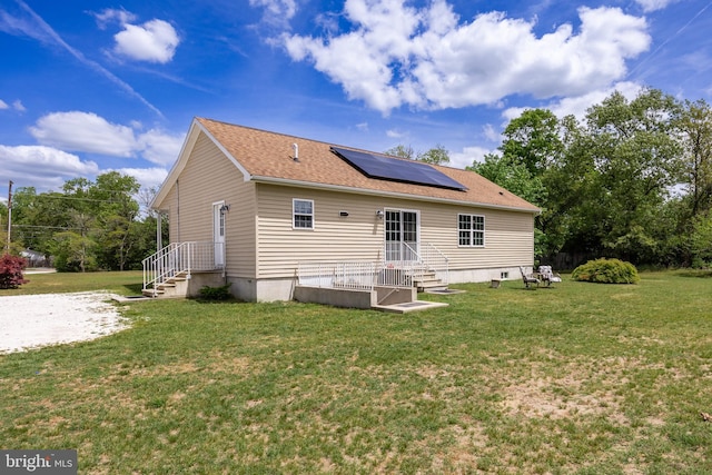 rear view of house featuring a lawn and solar panels