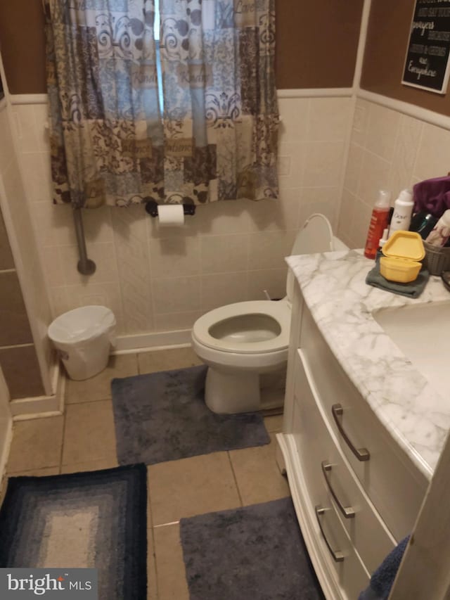 bathroom with tile flooring, tile walls, toilet, and vanity