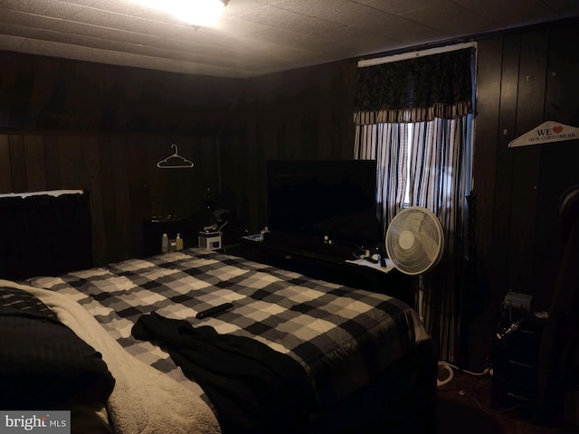 bedroom featuring wood walls and dark carpet