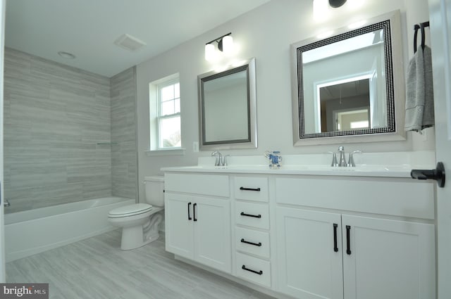 full bathroom featuring vanity, tiled shower / bath combo, and toilet