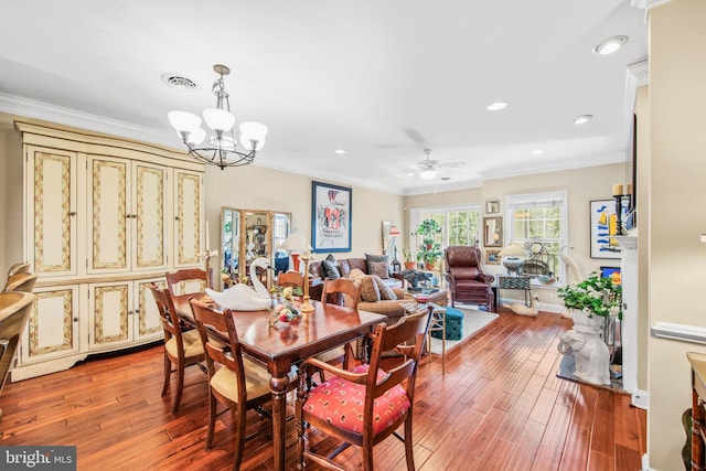 dining area featuring hardwood / wood-style floors, ornamental molding, and ceiling fan with notable chandelier