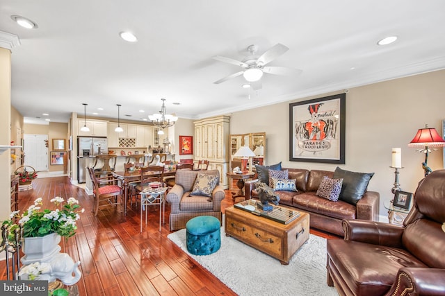 living room featuring hardwood / wood-style flooring, ceiling fan with notable chandelier, and ornamental molding