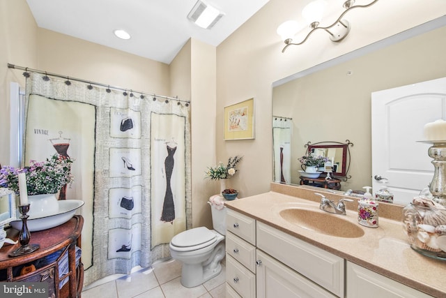 bathroom with toilet, vanity, and tile patterned flooring