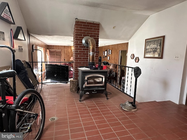 interior space featuring wood walls, lofted ceiling, brick wall, and a wood stove