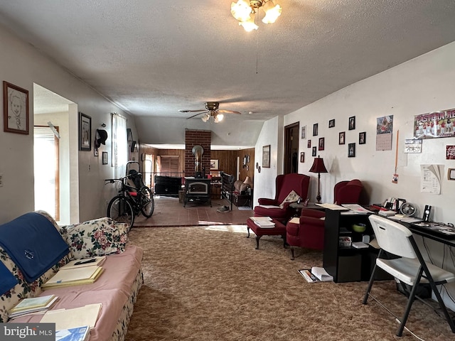 interior space featuring dark tile floors, a textured ceiling, ceiling fan, and a wood stove