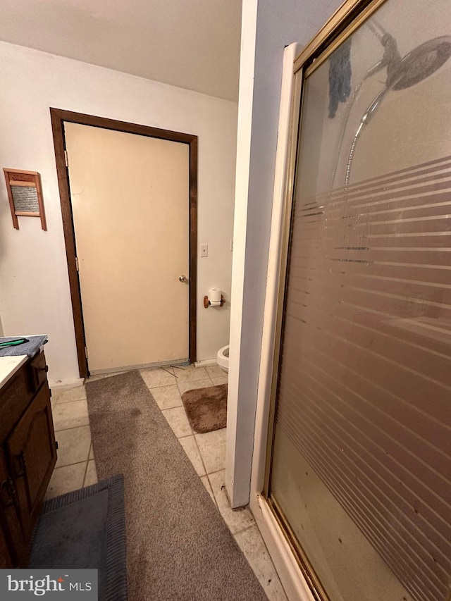 bathroom with walk in shower, toilet, tile flooring, and vanity