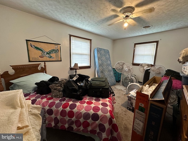 carpeted bedroom with multiple windows, ceiling fan, and a textured ceiling