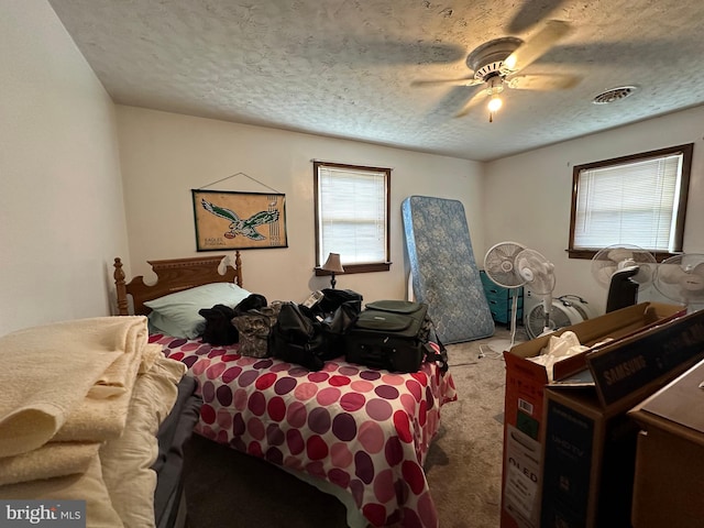 bedroom with multiple windows, a textured ceiling, light colored carpet, and ceiling fan