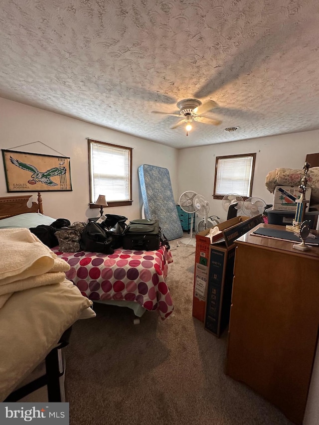 bedroom with ceiling fan, carpet flooring, and a textured ceiling