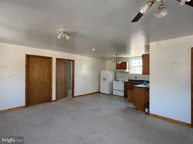 kitchen featuring white appliances, light carpet, ceiling fan with notable chandelier, and sink