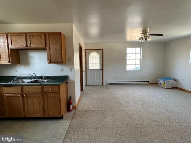 kitchen featuring ceiling fan, sink, a baseboard heating unit, and light colored carpet