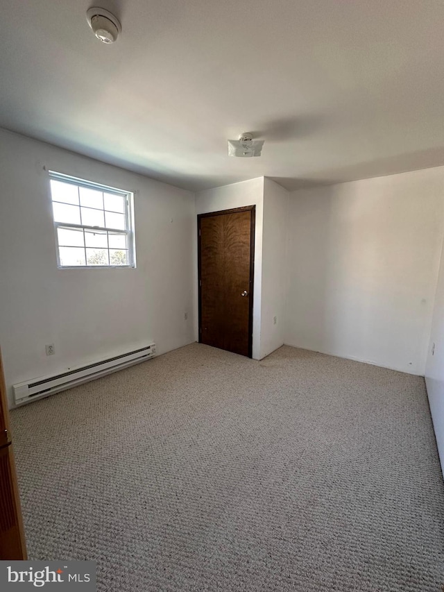 empty room featuring light carpet and a baseboard heating unit