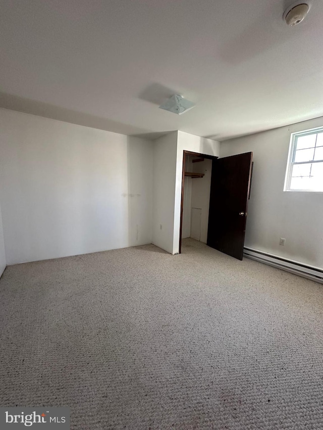 carpeted empty room featuring baseboard heating