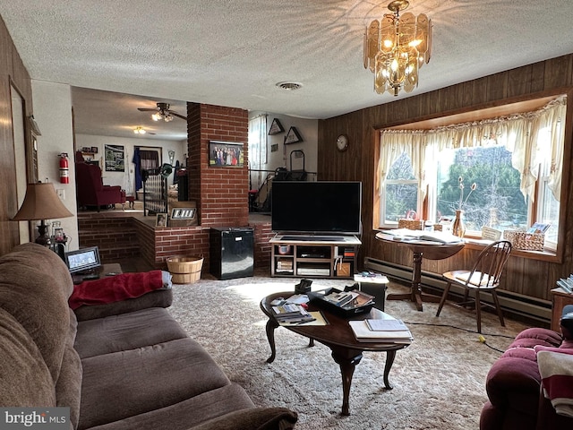 carpeted living room featuring wood walls, a textured ceiling, and ceiling fan with notable chandelier