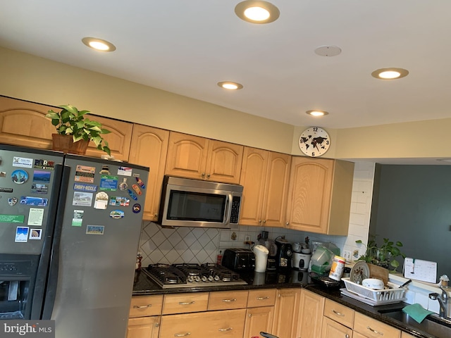 kitchen with tasteful backsplash, appliances with stainless steel finishes, sink, dark stone countertops, and light brown cabinets