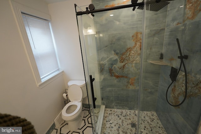 bathroom featuring a shower with door and toilet