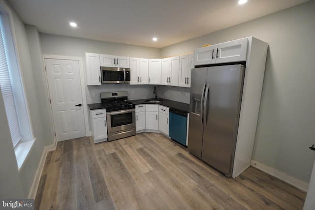 kitchen with white cabinetry, appliances with stainless steel finishes, and wood-type flooring