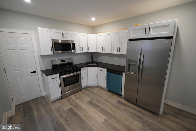 kitchen with dark wood-type flooring, white cabinets, stainless steel appliances, backsplash, and sink