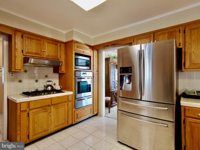 kitchen with light tile flooring, stainless steel appliances, tile countertops, and tasteful backsplash