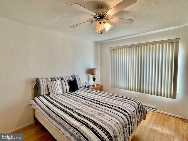 bedroom featuring a textured ceiling, ceiling fan, and light wood-type flooring