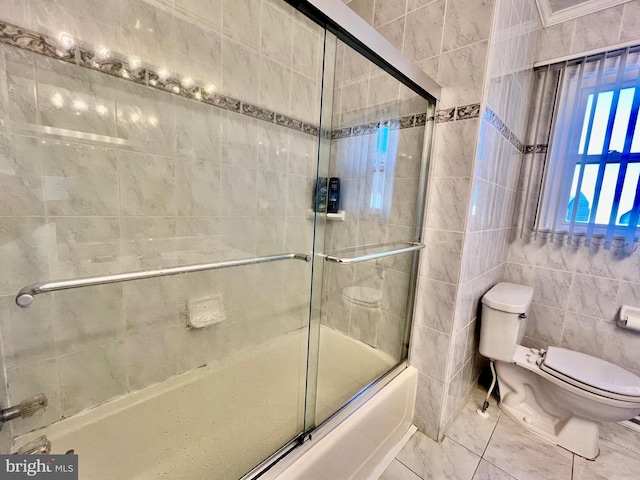 bathroom with tile walls, toilet, enclosed tub / shower combo, and tile floors