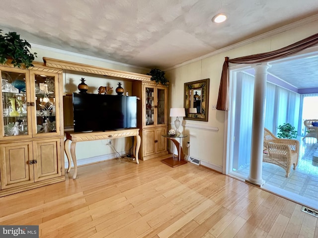 living room with ornamental molding, decorative columns, and light wood-type flooring