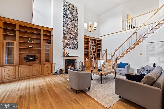 living room featuring an inviting chandelier, light hardwood / wood-style floors, and a high ceiling