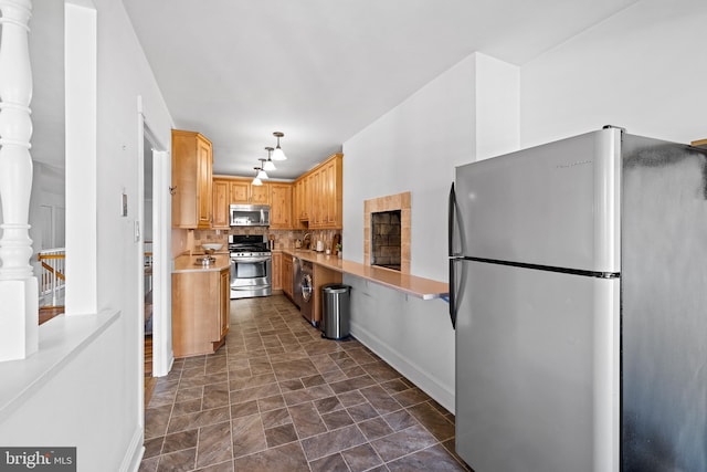 kitchen featuring pendant lighting, stainless steel appliances, washer / dryer, backsplash, and dark tile floors