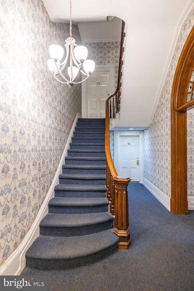 stairs featuring a notable chandelier, crown molding, and dark colored carpet