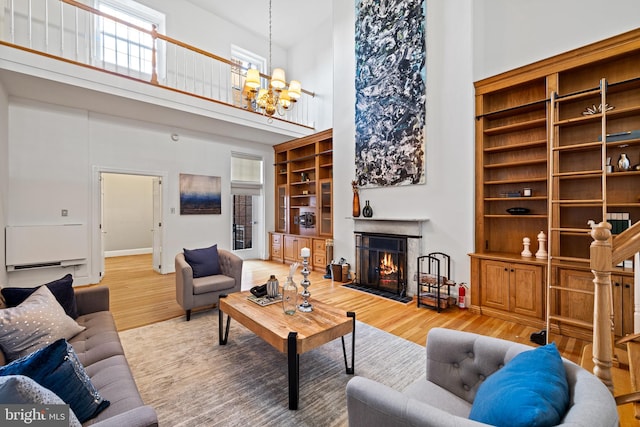 living room featuring a chandelier, a high ceiling, and light hardwood / wood-style flooring