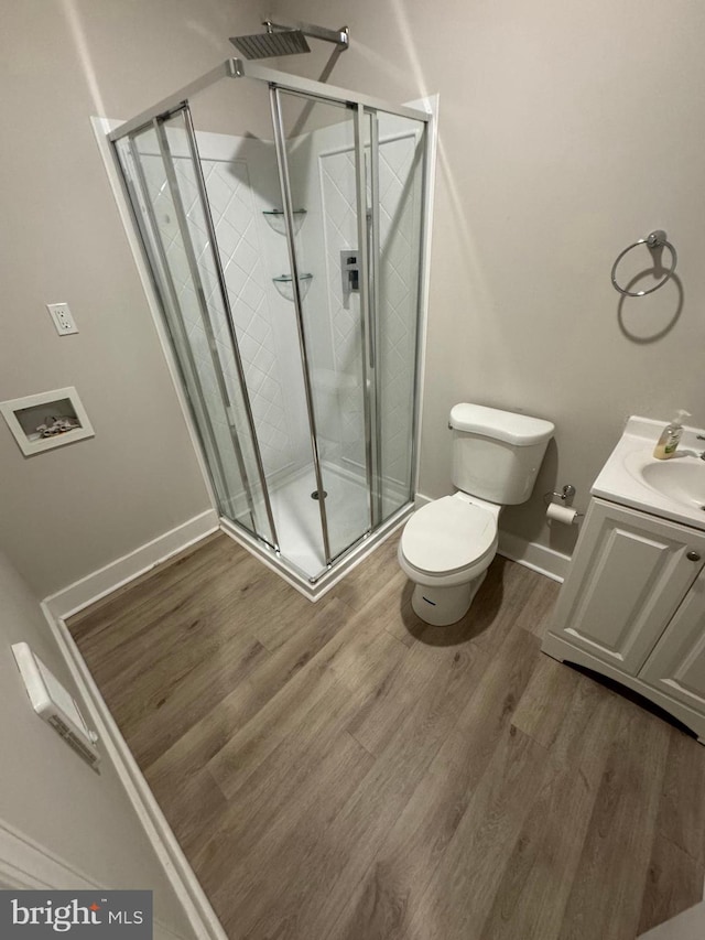 bathroom with wood-type flooring, vanity, toilet, and a shower with shower door