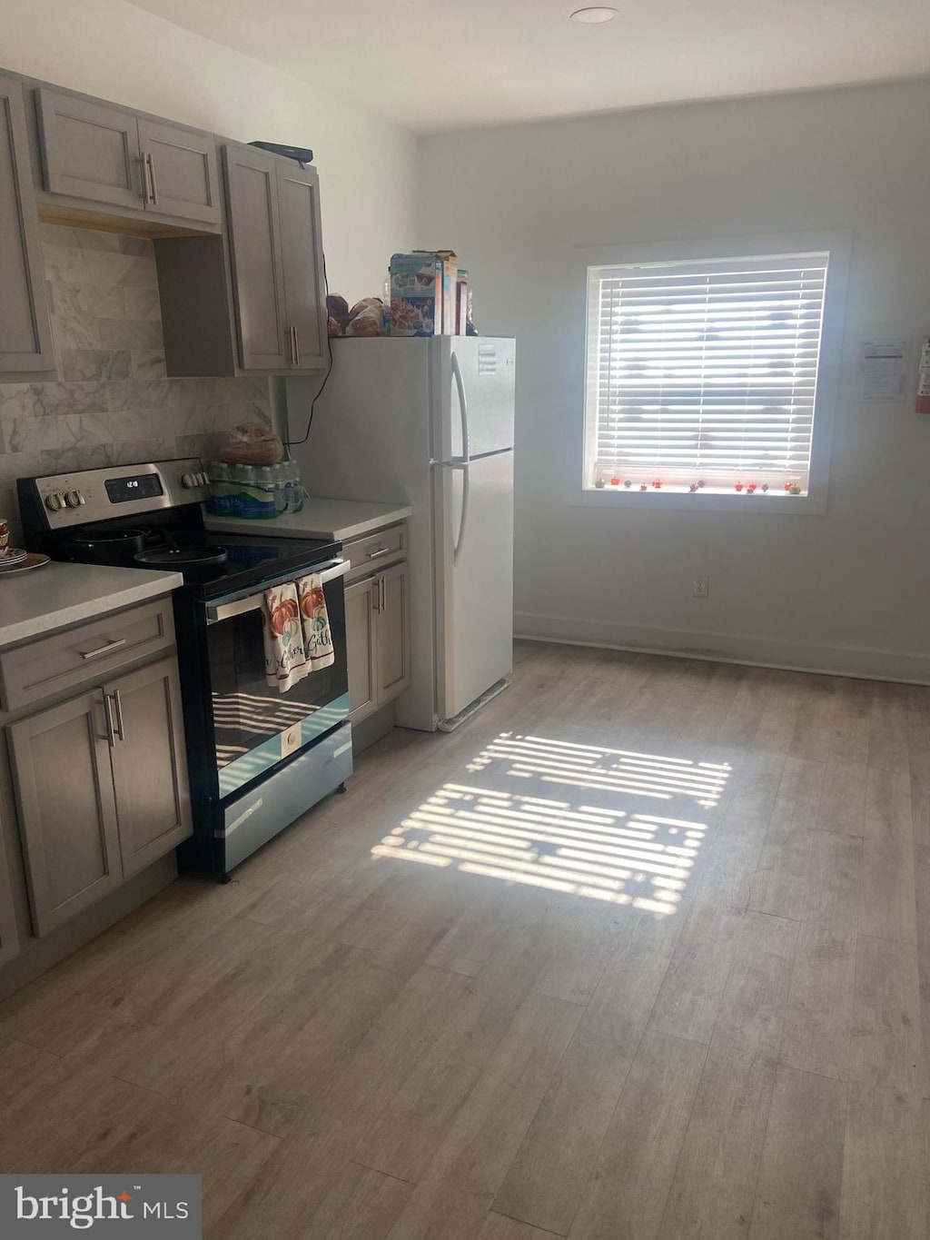 kitchen with electric stove, gray cabinetry, and light hardwood / wood-style flooring