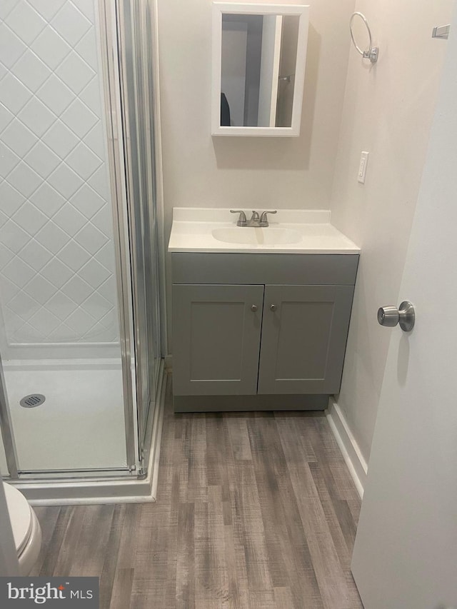 bathroom featuring an enclosed shower, toilet, wood-type flooring, and vanity