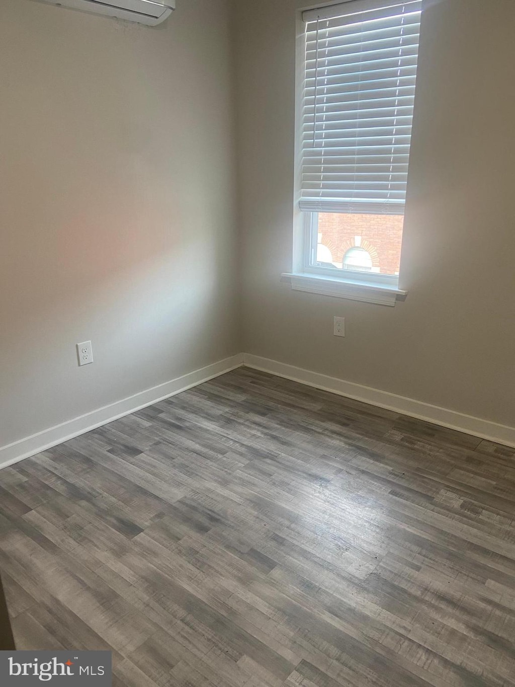 unfurnished room with dark hardwood / wood-style flooring and an AC wall unit