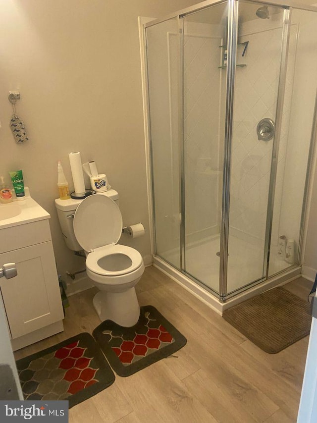 bathroom featuring an enclosed shower, vanity, toilet, and hardwood / wood-style flooring