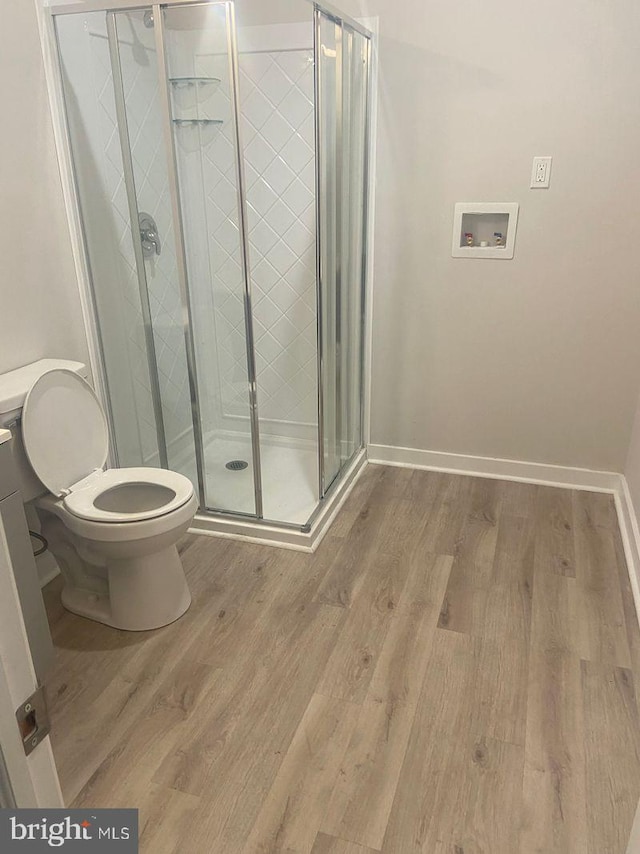 bathroom with an enclosed shower, hardwood / wood-style flooring, and toilet