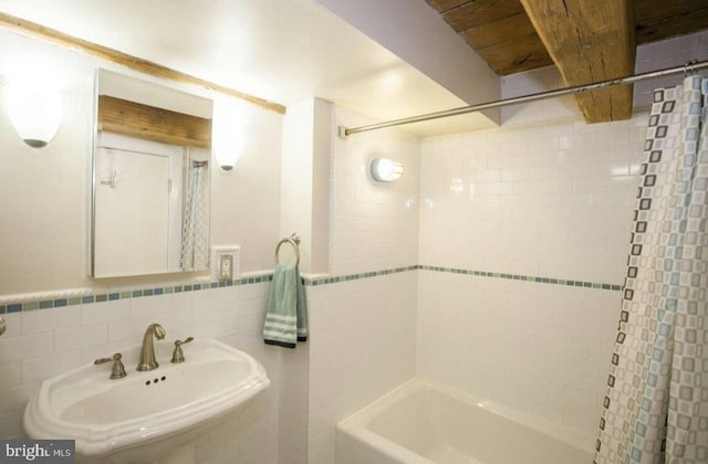 bathroom featuring tile walls, shower / bathtub combination with curtain, and sink