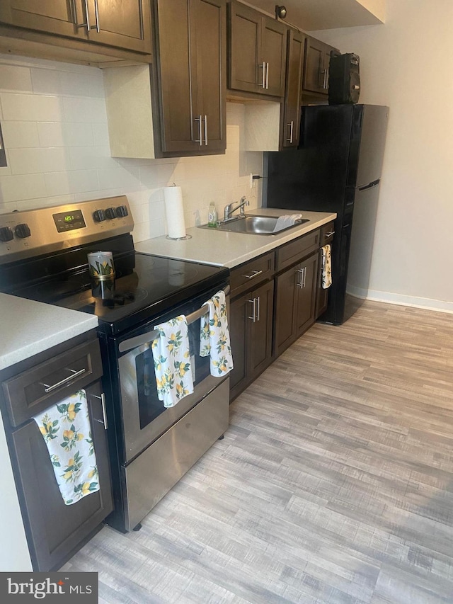 kitchen featuring sink, light wood-type flooring, dark brown cabinetry, and stainless steel electric range oven