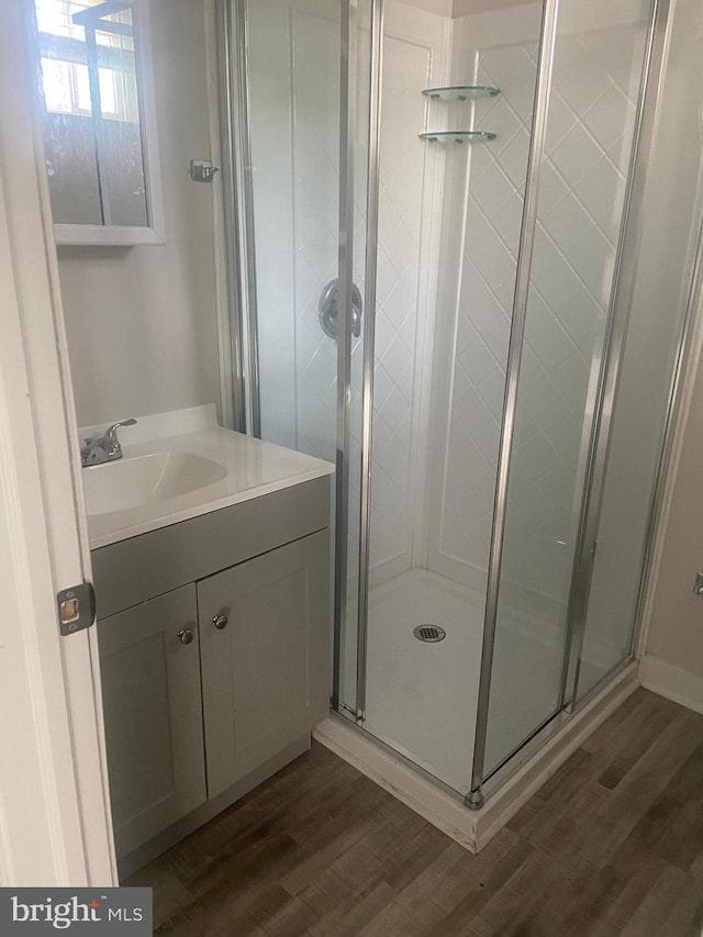 bathroom featuring vanity with extensive cabinet space, walk in shower, and hardwood / wood-style flooring