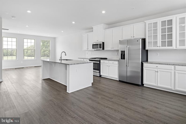 kitchen featuring dark hardwood / wood-style floors, a center island with sink, light stone countertops, white cabinets, and appliances with stainless steel finishes